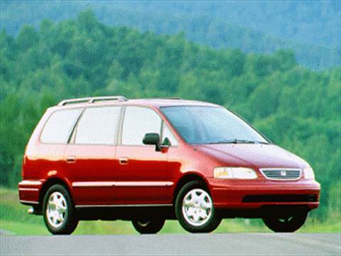 A red 1995 Honda Odyssey minivan on a road with trees in the background.