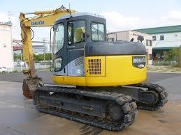 A yellow and black Komatsu PC128us-2 construction vehicle with its bucket arm extended.