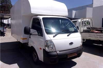 A white 2005 Kia K2700 van with the back open, possibly for loading or unloading cargo.